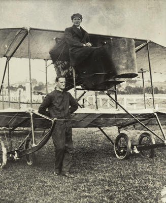 Black and white photograph of Miller and Sandford and their plane which was rebuilt from the Walsh brothers' Manurewa, Miller in the cockpit, Sandford standing